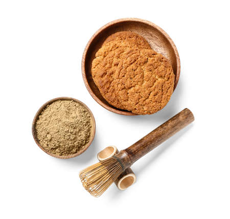 Bowl with hojicha powder, cookies and chasen on white background