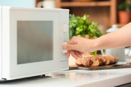 Housewife adjusting modern microwave oven in kitchen, closeupの写真素材