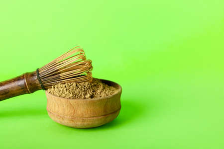 Bowl with hojicha powder and chasen on green background