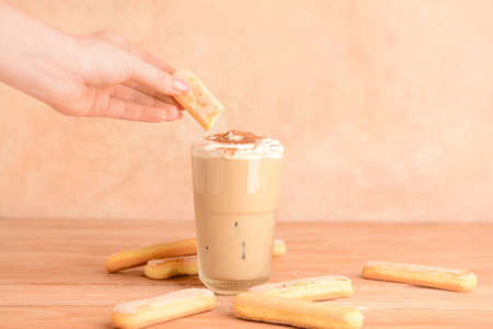 Woman preparing tasty Tiramisu Latte at table