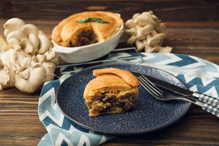 Plate with piece of tasty mushroom pot pie on wooden backgroundの写真素材