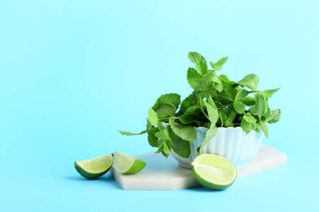 Bowl with fresh mint and cut lime on color background
