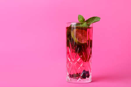 Glass of tasty cocktail with lime and mint on color background