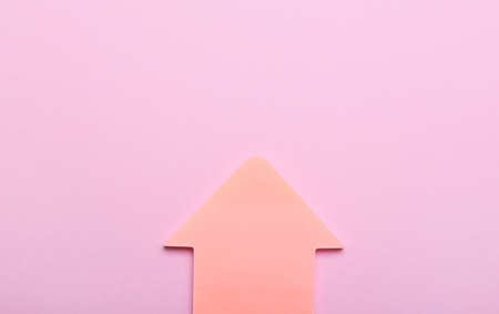 Sticky notes in shape of arrow on pink backgroundの写真素材