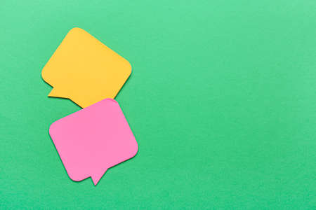 Sticky note papers in shape of speech bubbles on green background