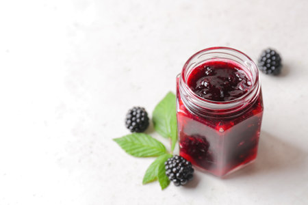 Jar of tasty blackberry jam on light backgroundの写真素材