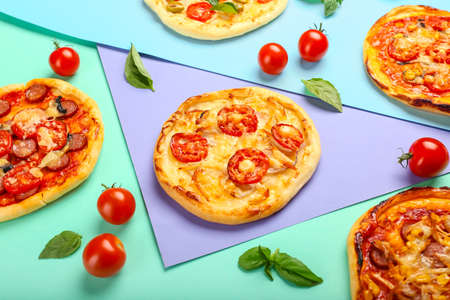 Delicious mini pizzas on color background