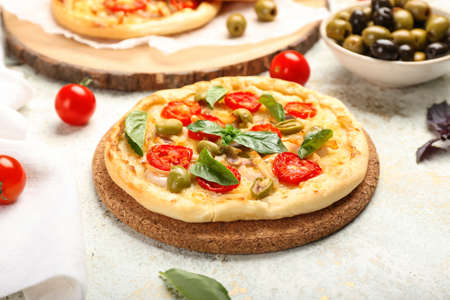 Board with tasty mini pizza on light background, closeup