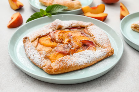 Plate with tasty peach galette on light background, closeupの写真素材