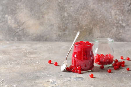 Jars of red currant jam and berries on grunge background