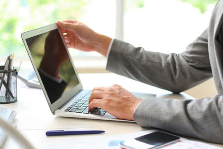 Businessman working with laptop at table in office, closeupの写真素材