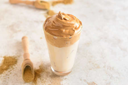 Glass of tasty dalgona hojicha latte and powder on light backgroundの写真素材
