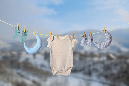 Baby clothes and toys hanging on rope outdoorsの写真素材