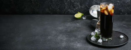 Glass of tasty Cuba Libre cocktail on dark background with space for text