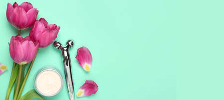 Tulips, jar of cream and facial massage tool on turquoise background with space for text. mother's...