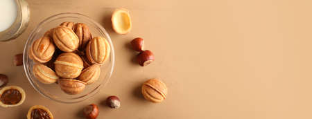 Bowl of tasty walnut shaped cookies with boiled condensed milk on color background with space for textの写真素材