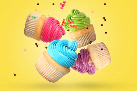 Tasty flying cupcakes on yellow background