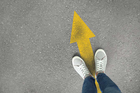 Man standing on asphalt road with drawn arrow, top viewの写真素材
