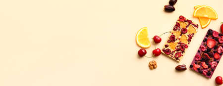Tasty chocolate bars with fruits and nuts on light background with space for textの写真素材