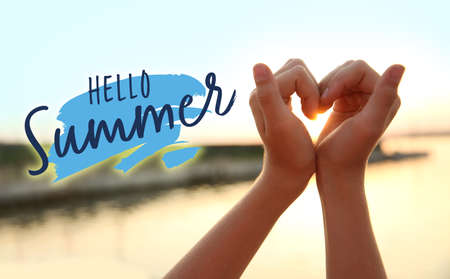 Cute little girl making heart with her hands outdoors at sunset. hello summerの写真素材