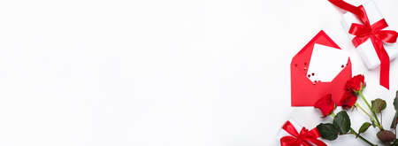 Gift boxes, envelope and red roses on white background with space for textの写真素材