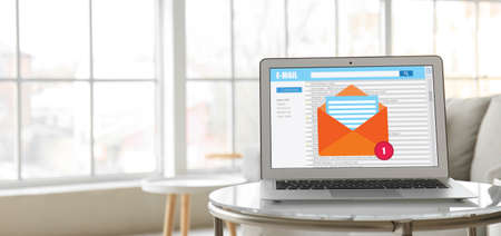 Laptop with symbol of new unread message on screen in room