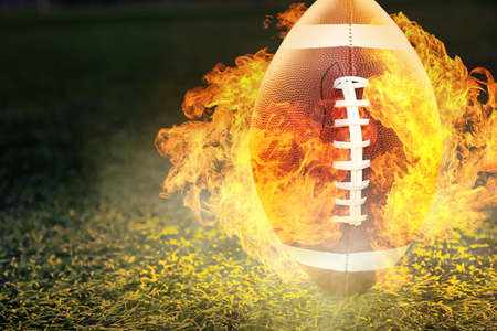 Burning rugby ball on green field outdoors
