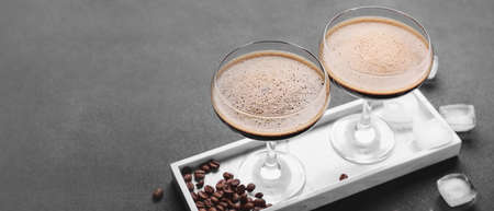 Two glasses of tasty espresso martini cocktail on gray table