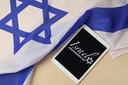 Tablet computer with text ISRAEL INDEPENDENCE DAY on screen and flag on light backgroundの写真素材