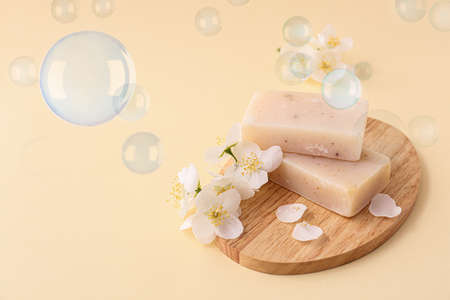 Board with soap bars and flowers on light color backgroundの写真素材