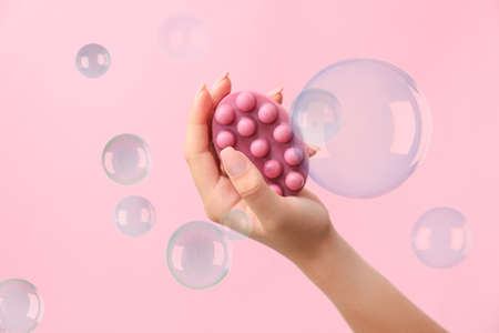 Female hand with massage soap bar and many bubbles on pink backgroundの写真素材