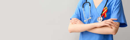 Female doctor with awareness ribbon and stethoscope on gray background with space for text. Hepatitis conceptの写真素材