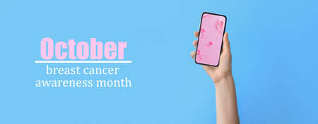 Hand holding mobile phone with pink ribbons on screen and text OCTOBER - BREAST CANCER AWARENESS...