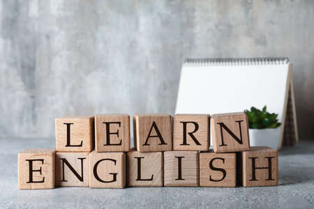 Text LEARN ENGLISH made of wooden cubes on table