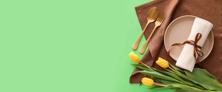 Beautiful spring table setting with tulips on green background with space for text