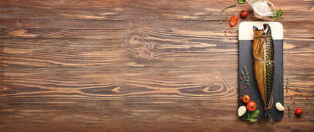 Board with tasty smoked mackerel fish on wooden background with space for textの写真素材