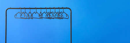 Rack with clothes hangers on blue background with space for textの写真素材