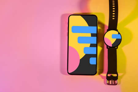 Modern mobile phone and smart watch on color background, top view