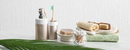 Different bath accessories on table against light background