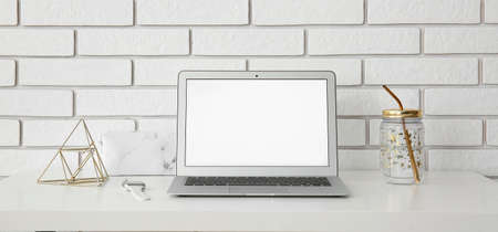 Workplace with modern laptop near white brick wallの写真素材