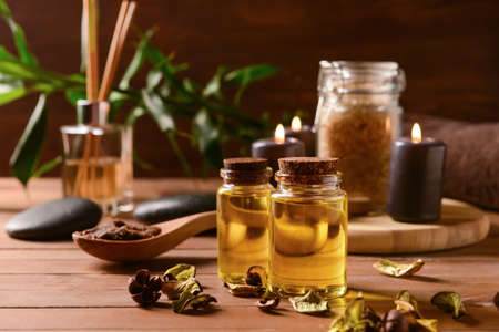 Bottles of essential oil and dried rose petals on wooden tableの写真素材