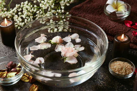 Glass bowl with water and rose petals on dark backgroundの写真素材