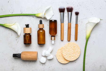 Composition with bottles of cosmetic products, makeup brushes, sponges and calla lilies on light backgroundの写真素材