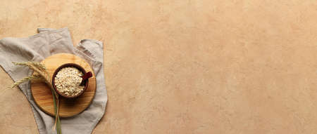 Bowl with raw oat flakes on grunge background with space for text