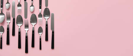 Many different cutlery on pink background with space for text
