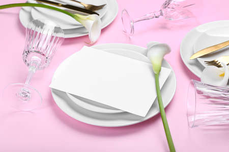 Beautiful table setting with calla lilies and blank card on pink background, closeup