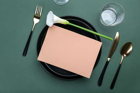 Beautiful table setting with blank card and calla lily on color background