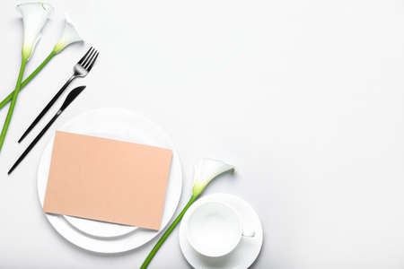 Beautiful table setting with blank card and calla lilies on white backgroundの写真素材
