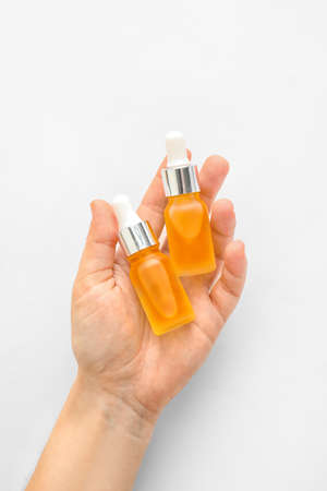 Woman holding bottles of essential oil on white background, closeupの写真素材