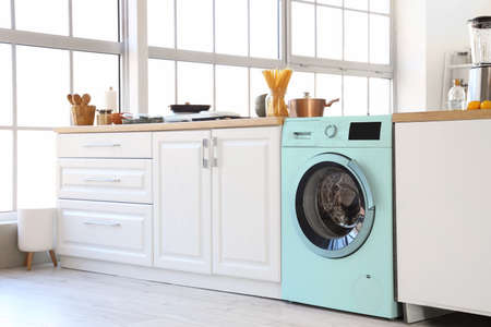 Interior of modern kitchen with turquoise washing machine